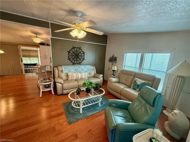 Living room with wood finished floors, wood walls, and ceiling fan