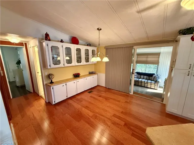 Unfurnished dining area with light wood-style floors, lofted ceiling, and crown molding