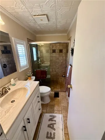 Bathroom with crown molding, vanity, a stall shower, light tile patterned flooring, and an ornate ceiling
