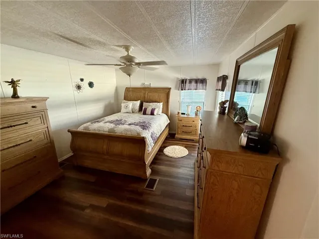 Bedroom featuring a textured ceiling, dark wood finished floors, and a ceiling fan
