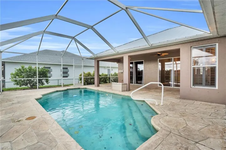 View of swimming pool featuring a patio, glass enclosure, and ceiling fan