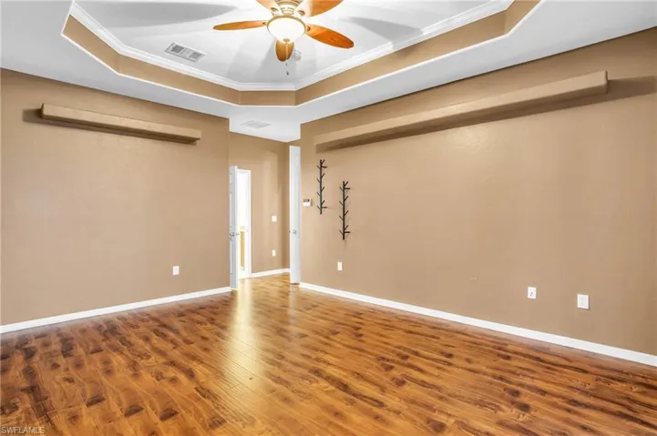 Master Bedroom featuring ceiling fan, ornamental molding, hardwood / wood vinyl floors, and a tray ceiling