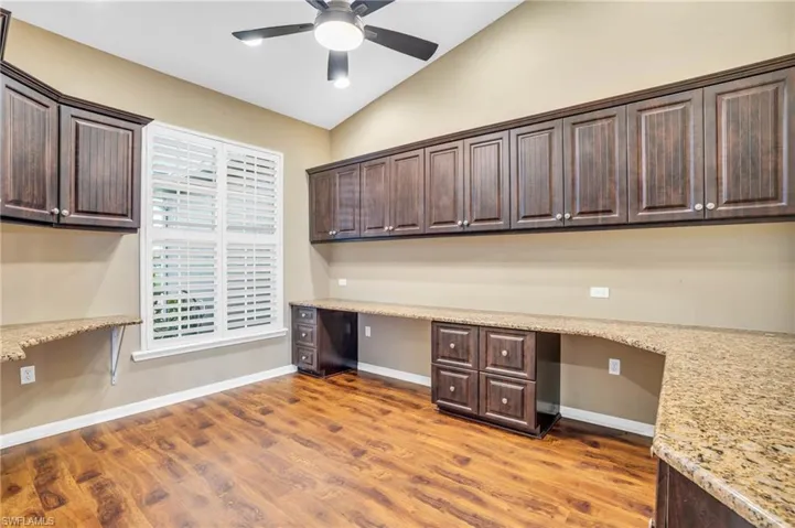 Office with cabinets, built in desk, and vaulted ceiling