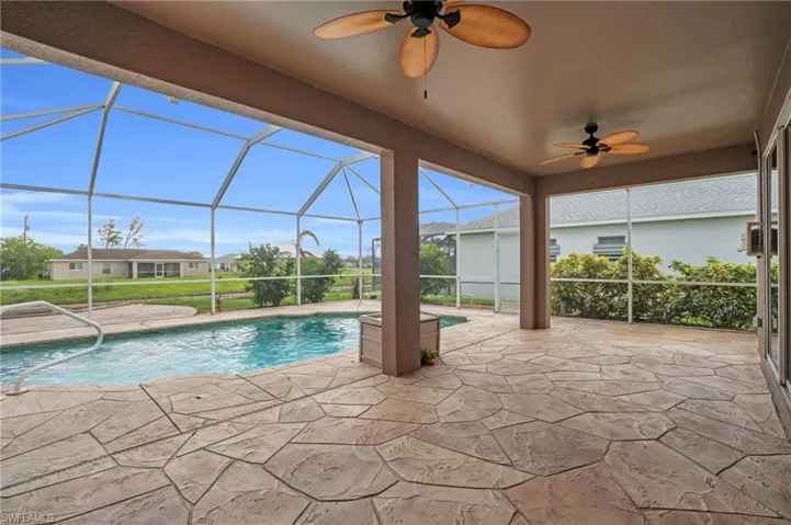View of swimming pool with ceiling fan, a patio area, and a lanai