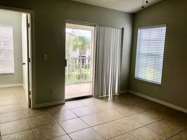 Empty room featuring light tile patterned floors, a textured ceiling, and plenty of natural light