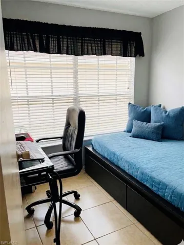 DEN / Bedroom with an office area and light tile patterned flooring. Staging .
