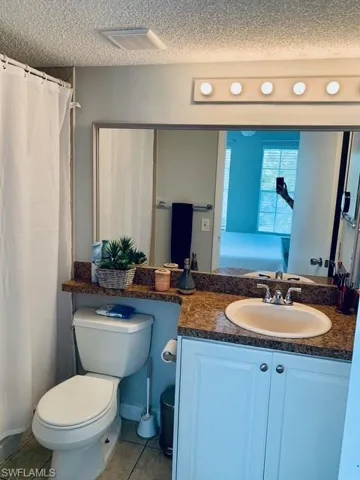 Bathroom featuring a textured ceiling, vanity, tile patterned flooring, and curtained shower