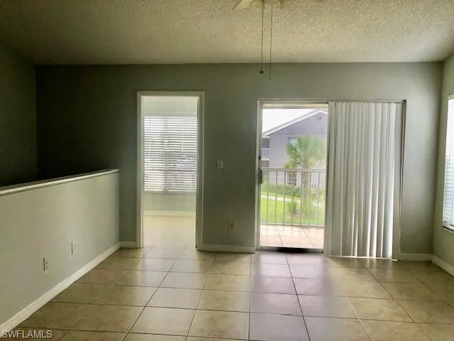 Empty room featuring healthy amount of natural light, light tile patterned floors, and a textured ceiling