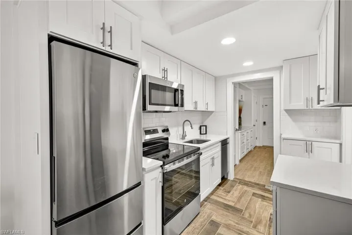 Kitchen featuring stainless steel appliances, recessed lighting, white cabinetry, and backsplash