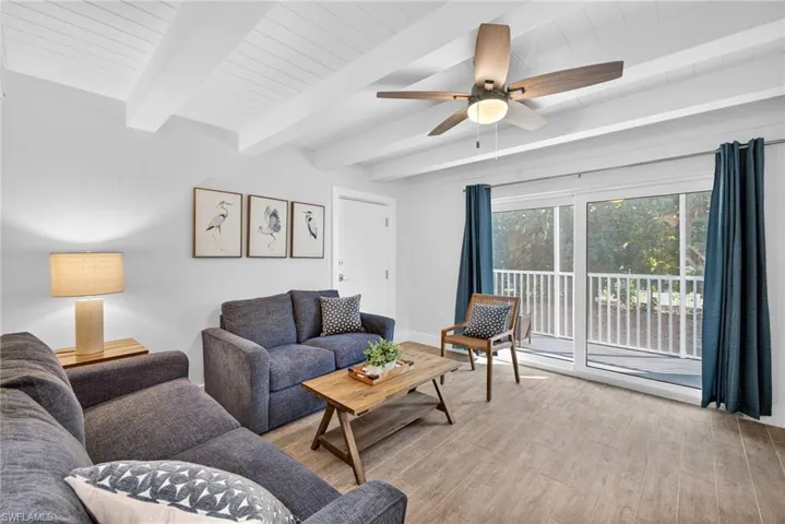 Living area featuring beam ceiling, ceiling fan, and light wood-style flooring