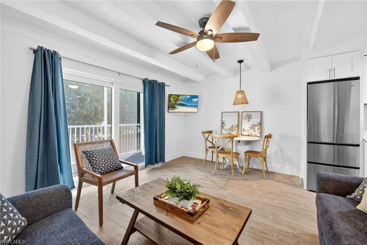 Living room with beam ceiling, light wood-style flooring, and ceiling fan