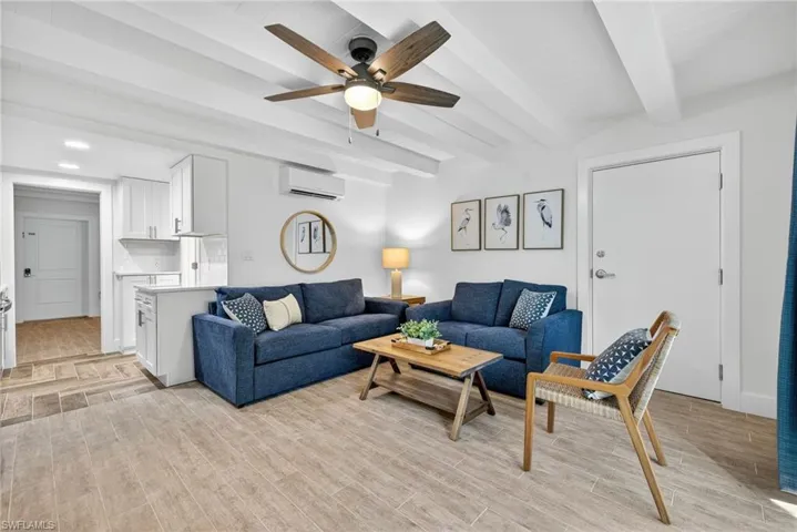 Living room with wood tiled floors, beamed ceiling, a ceiling fan, and a wall mounted air conditioner