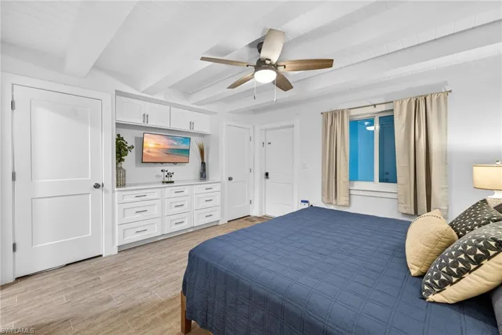 Bedroom featuring beam ceiling, ceiling fan, and light wood-type flooring