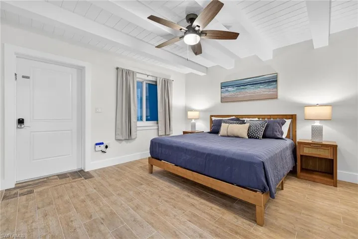 Bedroom with beamed ceiling, light wood-style flooring, and a ceiling fan