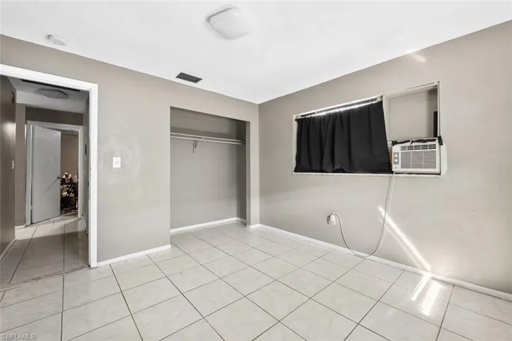 Unfurnished bedroom featuring cooling unit, a closet, and light tile patterned floors