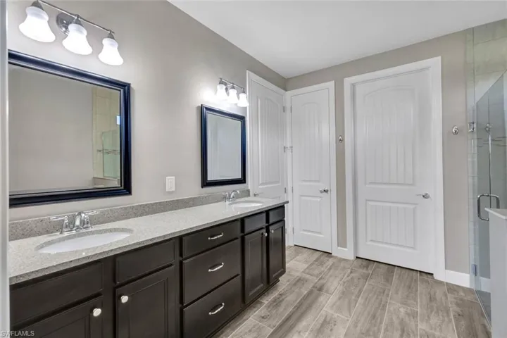 Master bathroom with double sinks, quartz counters and large glass shower.