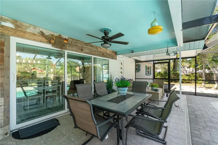 View of patio featuring ceiling fan, glass enclosure, and outdoor dining area