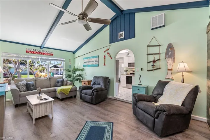 Living room with beamed ceiling, wood finished floors, high vaulted ceiling, arched walkways, and ceiling fan