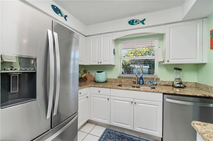 Kitchen featuring stainless steel appliances, white cabinetry, and light stone counters