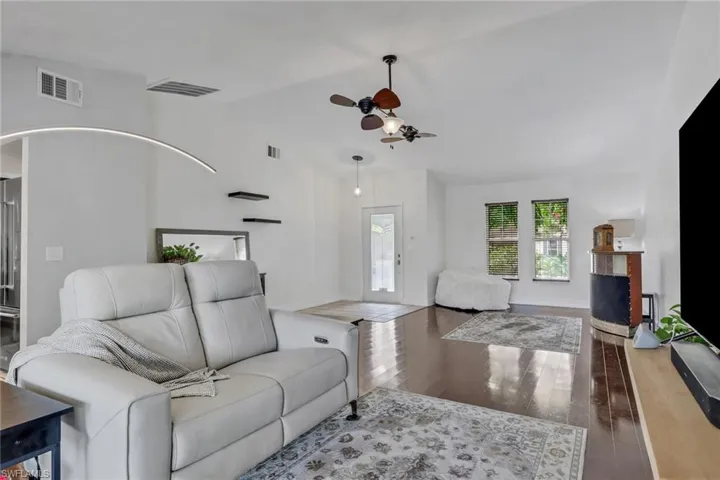 Living area with dark wood-style flooring, lofted ceiling, and a ceiling fan