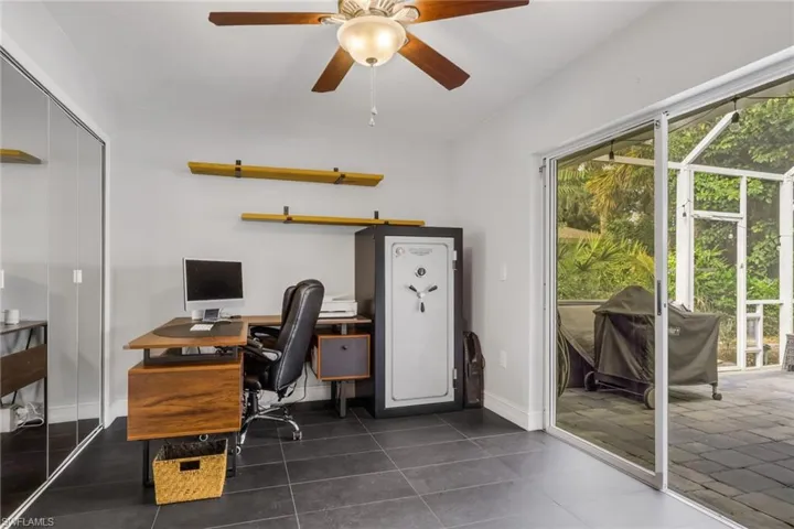 Office with ceiling fan, dark tile patterned floors, and a sunroom