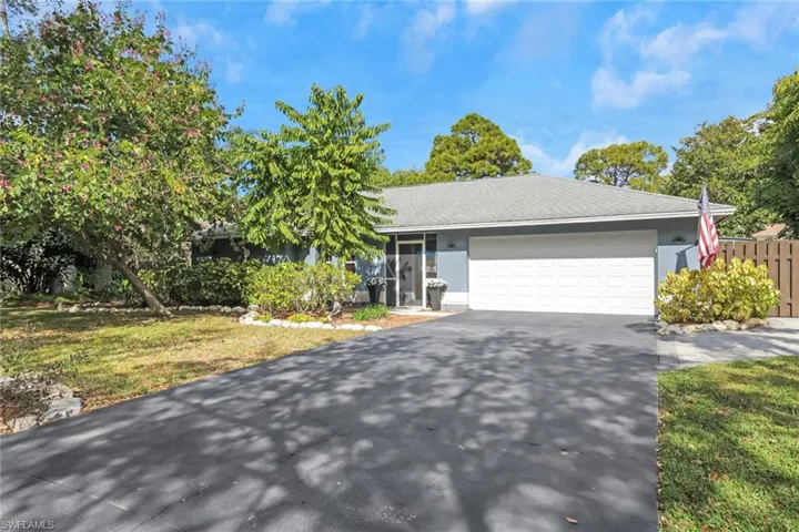 View of front of property featuring asphalt driveway, an attached garage, a front lawn, and stucco siding