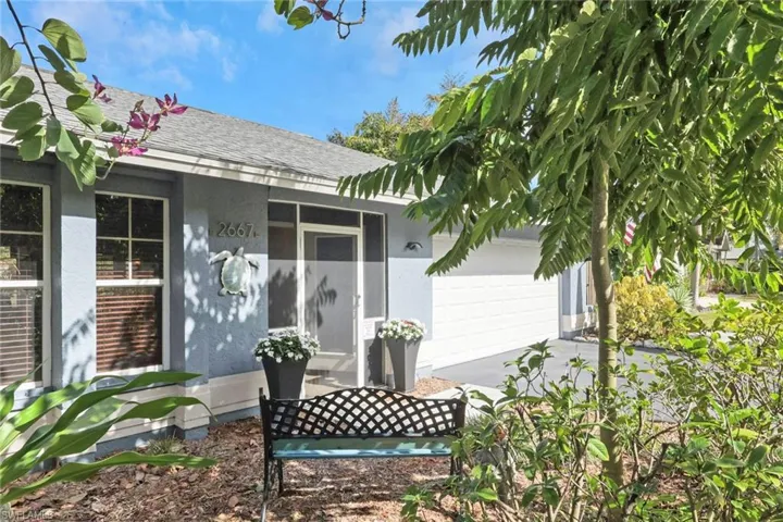 View of exterior entry featuring a shingled roof, stucco siding, an attached garage, and concrete driveway
