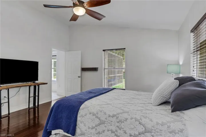 Bedroom featuring wood-type flooring, a ceiling fan, multiple windows, and lofted ceiling
