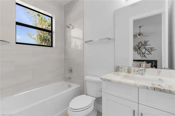 Full bathroom with vanity, toilet, ceiling fan, and tiled shower / bath