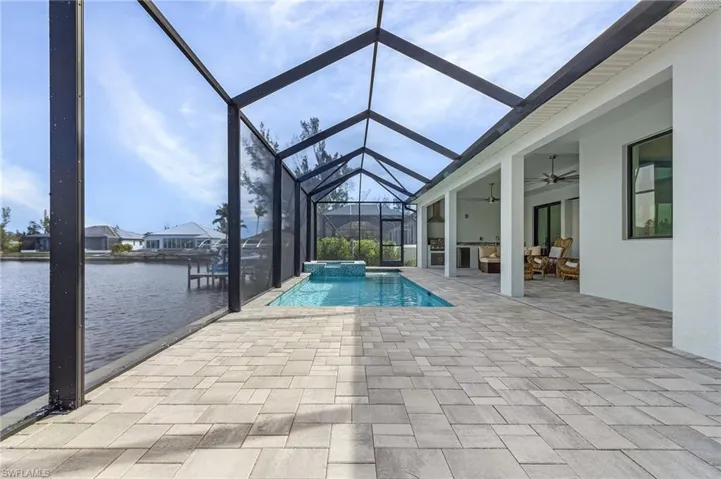View of pool featuring a water view, ceiling fan, a lanai, and a patio
