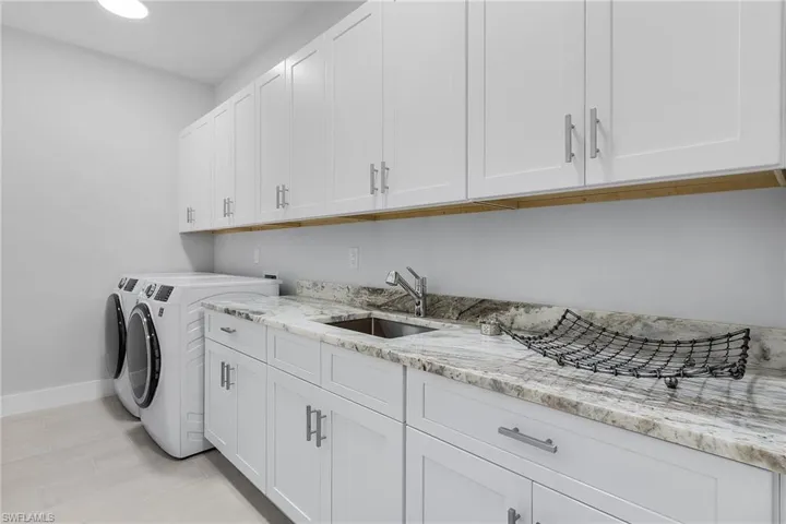 Clothes washing area with independent washer and dryer, cabinets, and sink