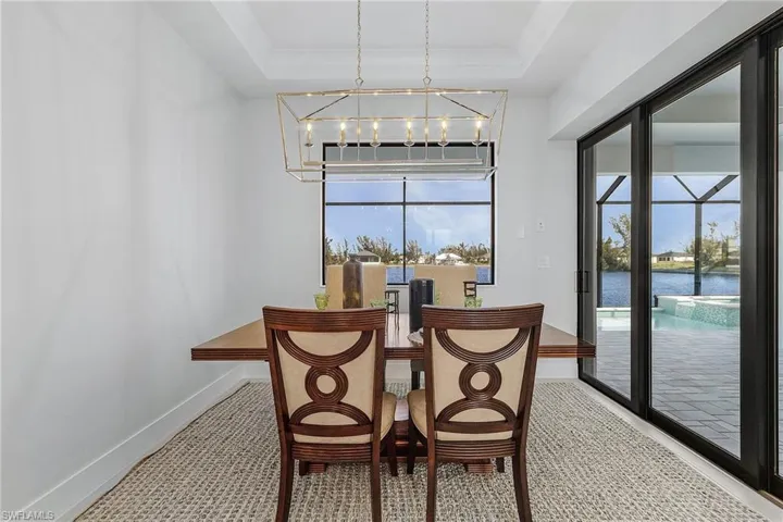 Dining room featuring a chandelier, a water view, carpet, and a raised ceiling