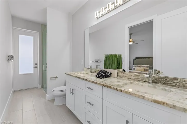 Bathroom with vanity, a shower with shower door, toilet, and ceiling fan