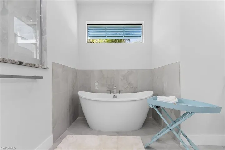 Bathroom featuring tile walls, tile patterned floors, and a washtub