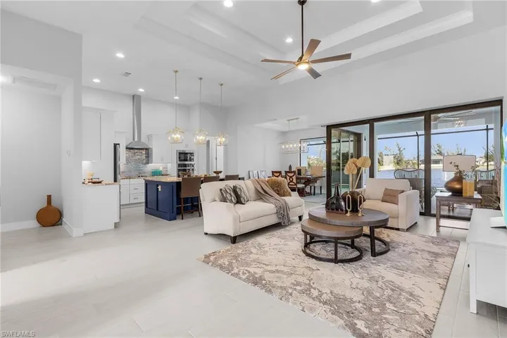 Living room with a tray ceiling and ceiling fan with notable chandelier