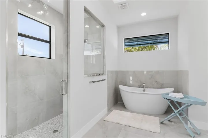 Bathroom with a healthy amount of sunlight, tile walls, and separate shower and tub