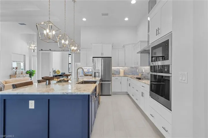 Kitchen featuring sink, a barn door, white cabinetry, a large island, and stainless steel appliances