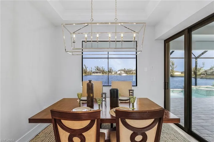 Dining room featuring a chandelier, a tray ceiling, and a healthy amount of sunlight