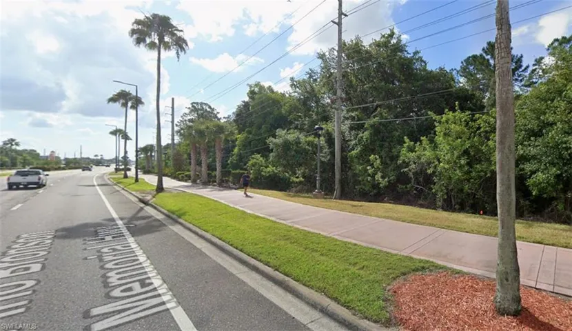 View of asphalt road featuring sidewalks, street lights, and curbs