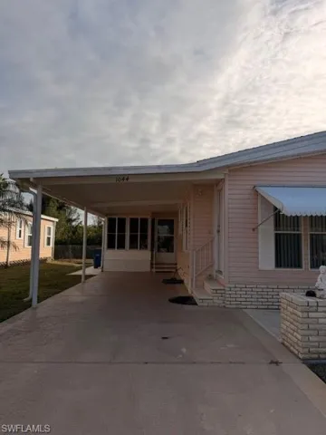View of front of property with a carport, a patio area, and concrete driveway