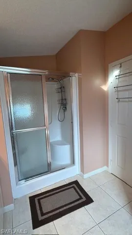 Bathroom featuring a stall shower, light tile patterned floors, and a textured ceiling