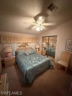 Bedroom featuring a textured ceiling, a ceiling fan, a closet, and carpet flooring