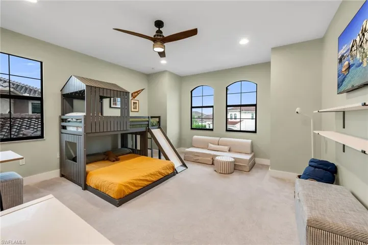 Spacious room featuring light-colored carpeting, three distinct windows with black frames, and recessed lighting