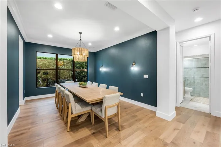 Spacious dining area featuring wood-finish flooring, a large window, recessed lighting, and a decorative chandelier