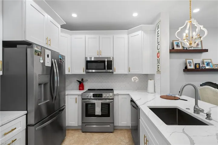 Kitchen featuring stainless steel appliances, white cabinets, and tasteful backsplash