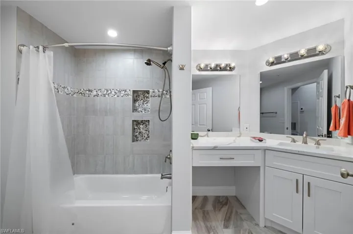 Full bathroom featuring shower / bathtub combination with curtain, vanity, and light wood-style flooring