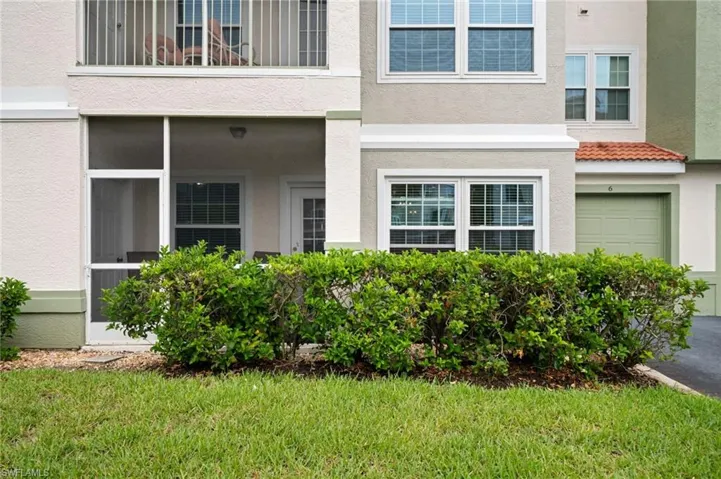 Doorway to property featuring stucco siding, a garage, a sunroom, and a lawn