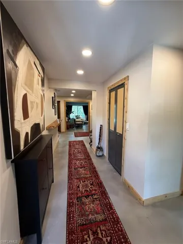 Hall featuring baseboards, recessed lighting, and concrete floors