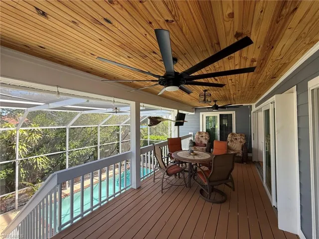 Wooden terrace featuring a patio area, a lanai, a ceiling fan, and an outdoor pool