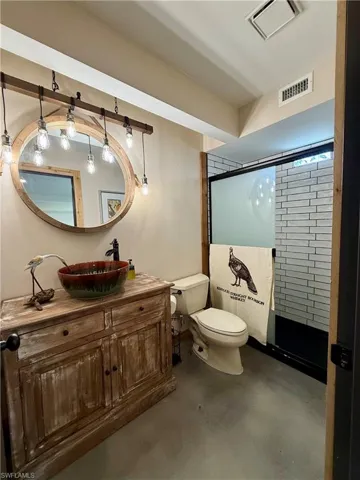 Bathroom featuring concrete floors, toilet, visible vents, and a shower stall